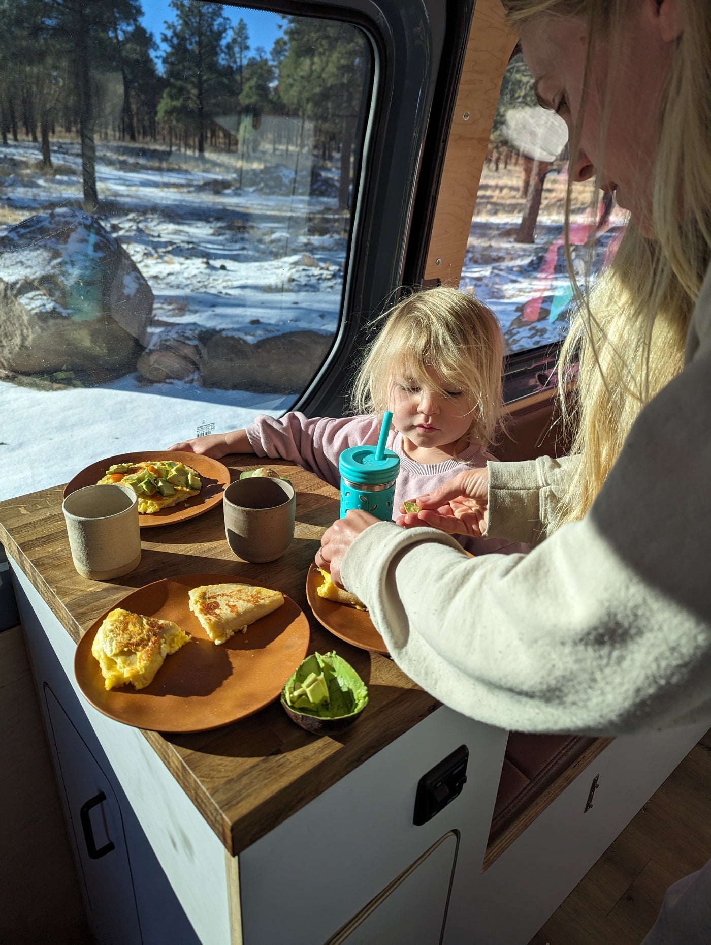 Cozy breakfast in an RV rental: a parent and child enjoy food with a view of a snowy forest outside. — photo 6