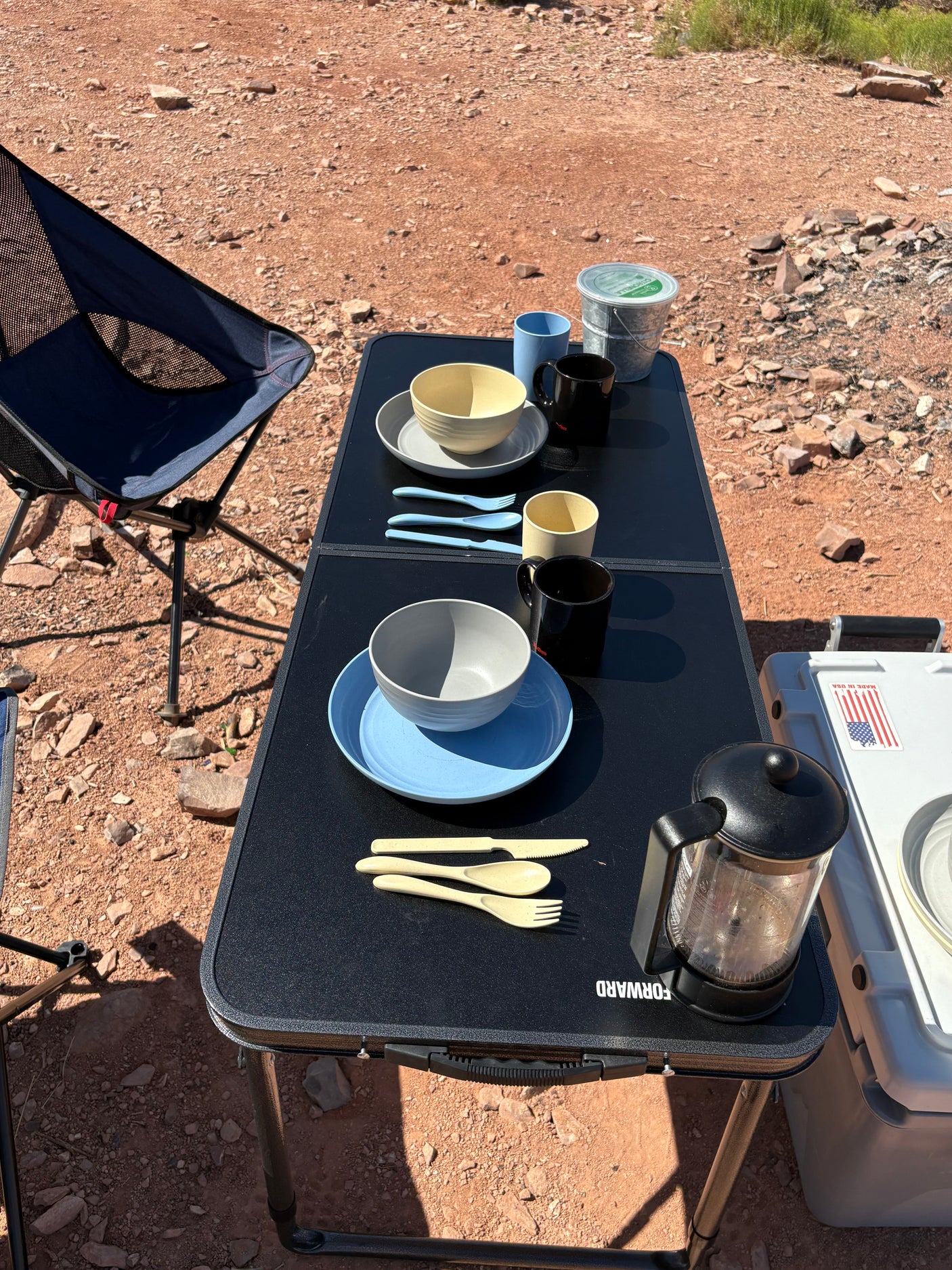 Outdoor dining setup on a portable table with tableware and French press, ideal for your RV rental campsite.