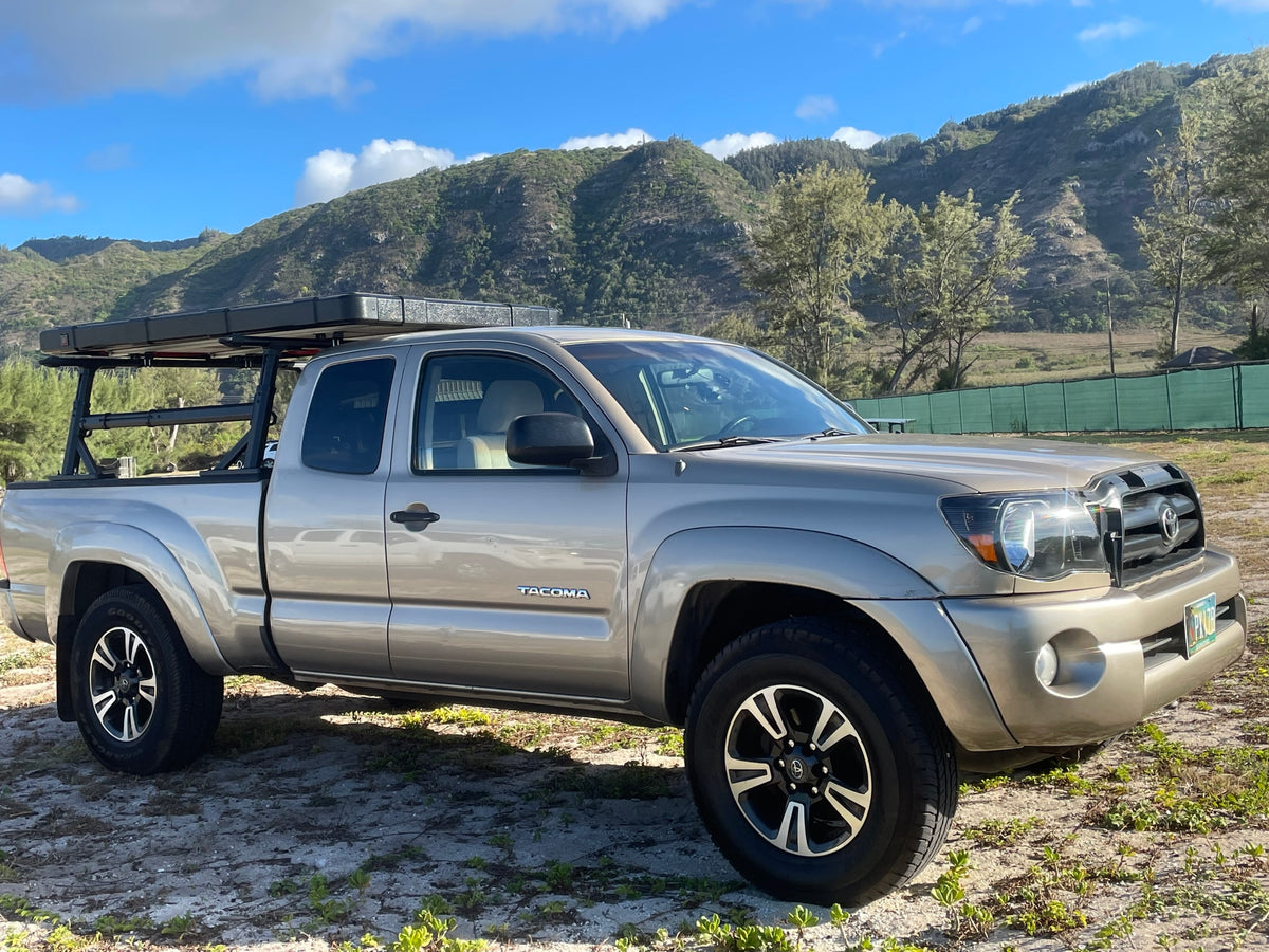 Tan Toyota Tacoma with an overland bed rack & rooftop tent parked in nature. Ideal for exploring and a unique RV rental experience. — photo 16
