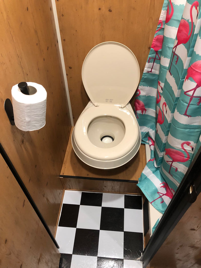 Inside an RV rental bathroom: a compact toilet, TP holder, vibrant flamingo shower curtain, and checkered floor mat. — photo 14
