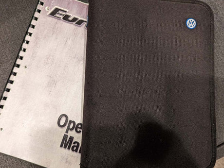 A black VW case and spiral-bound operating manual for an RV rental. Key vehicle info for the journey.