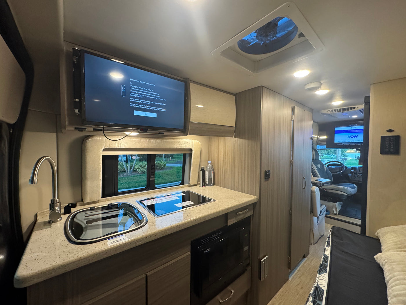 RV rental: Inside a modern RV with kitchen, sink, stove, microwave, and a TV showing a "remote not detected" message. — photo 12