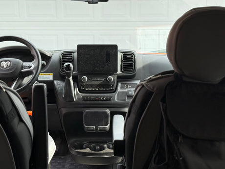 An RV rental van's interior dashboard with steering wheel, gear shift, and tablet mount. Note the pop top caution label.