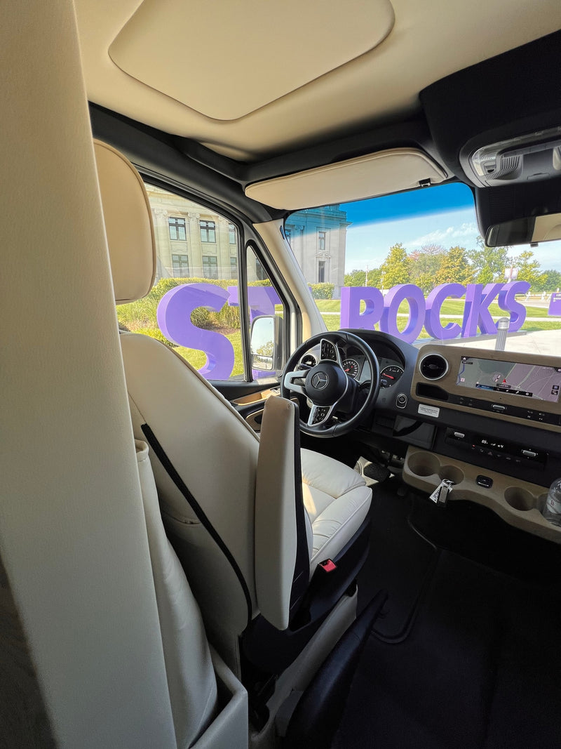 Luxury RV rental cockpit with cream seating, Mercedes-Benz steering wheel, and a large "ROCKS" sign visible outside. — photo 4