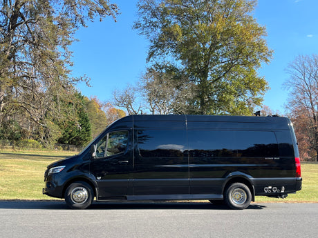 Black Mercedes-Benz Sprinter conversion van parked outside, ideal for luxury RV rental getaways under blue skies.