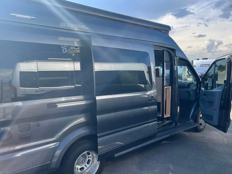 Dark gray camper van with open side and front doors, available as an RV rental. Ready for your road trip adventure.