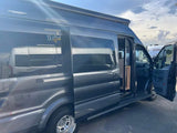 Dark gray camper van with open side and front doors, available as an RV rental. Ready for your road trip adventure.