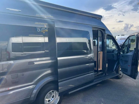 Dark gray camper van with open side and front doors, available as an RV rental. Ready for your road trip adventure.