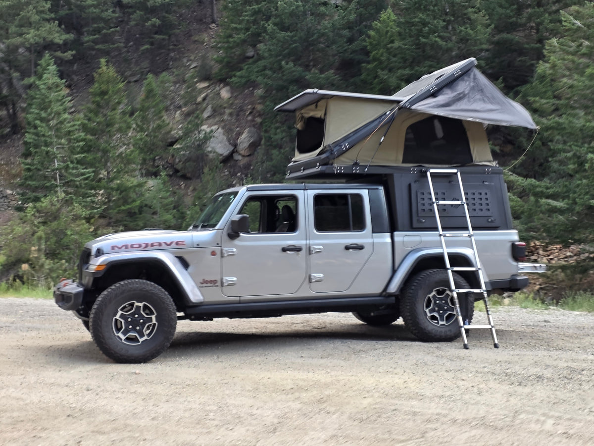 Jeep Gladiator Mojave with overland rooftop tent setup. An adventure RV rental for off-road camping in the wilderness.