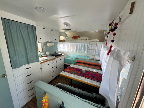 Bright rv rental interior featuring a kitchen, bunk beds, and a colorful dining area.