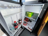 RV rental mini-fridge, neatly stocked with sparkling water, sodas, protein drinks, water, and cold brew coffee.