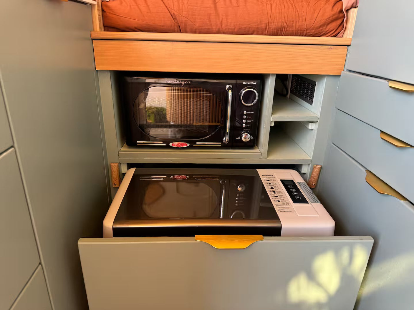 This RV rental features a compact kitchen with a black RetroWave microwave & a pull-out drawer holding a RongdY appliance. Smart storage!