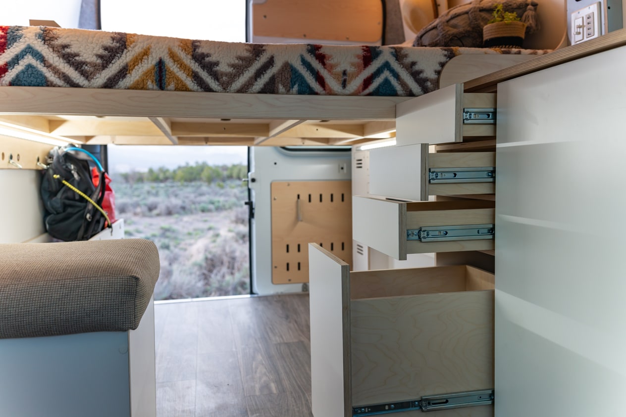  and wood paneling reveal a custom interior.|Modern RV rental kitchen: white cabinetry — photo 4