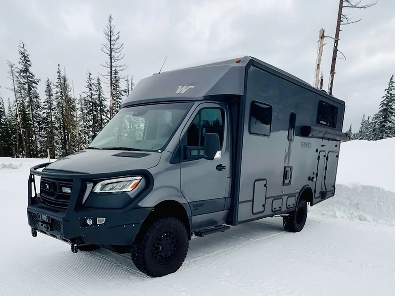  surrounded by a lush forest.|Adventure awaits with this rugged Mercedes Sprinter camper van rv rental parked by the ocean. Perfect for overlanding & beach camping.|Gray Winnebago EKKO RV rental in a snow-covered forest. Perfect for winter adventure travel.|Rugged gray RV rental parked in a vast snowy field. Its lights glow — photo 5
