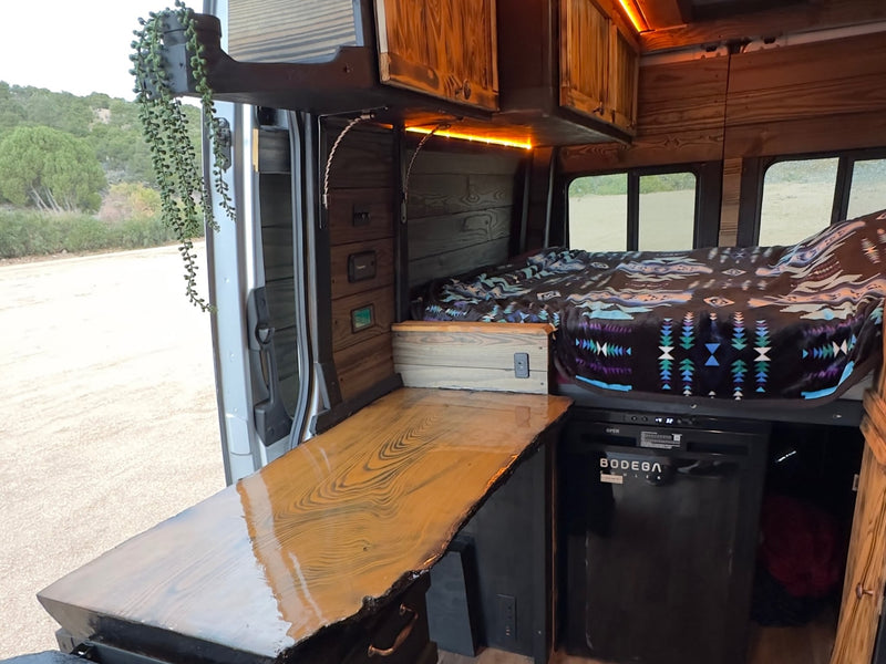  offering a scenic view of a dry lakebed and distant hills.|Cozy RV rental interior shows a bed with a patterned blanket — photo 7