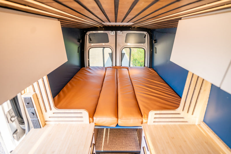 Inside a custom rv rental van: a warm, inviting interior with a brown bed, wood ceiling, and blue walls. — photo 5