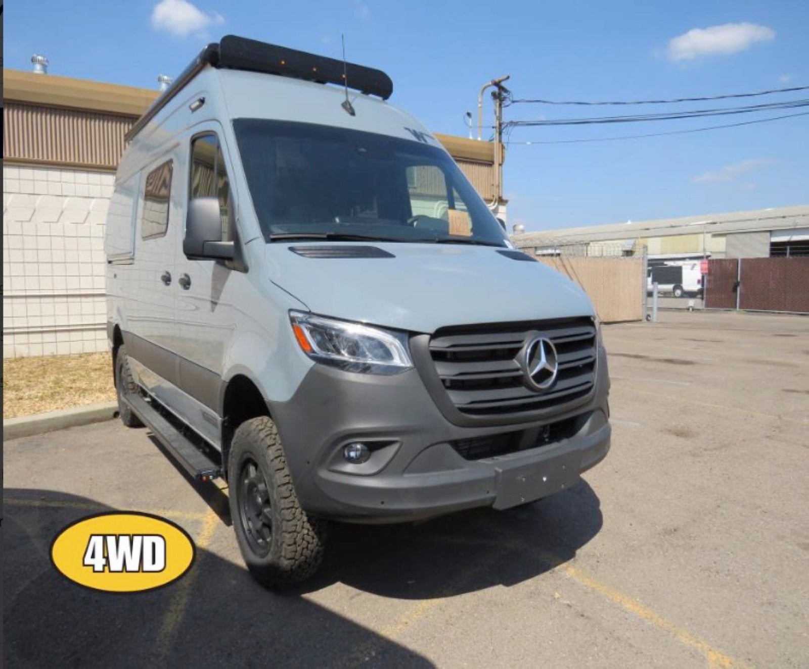 Light gray Mercedes-Benz Sprinter 4WD camper van, ideal for rv rental adventures. Features all-terrain tires, roof rack, and side steps.