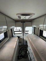 Interior view of a modern rv rental, featuring two comfortable beds, overhead storage, and a ceiling AC unit. Ideal for travel.