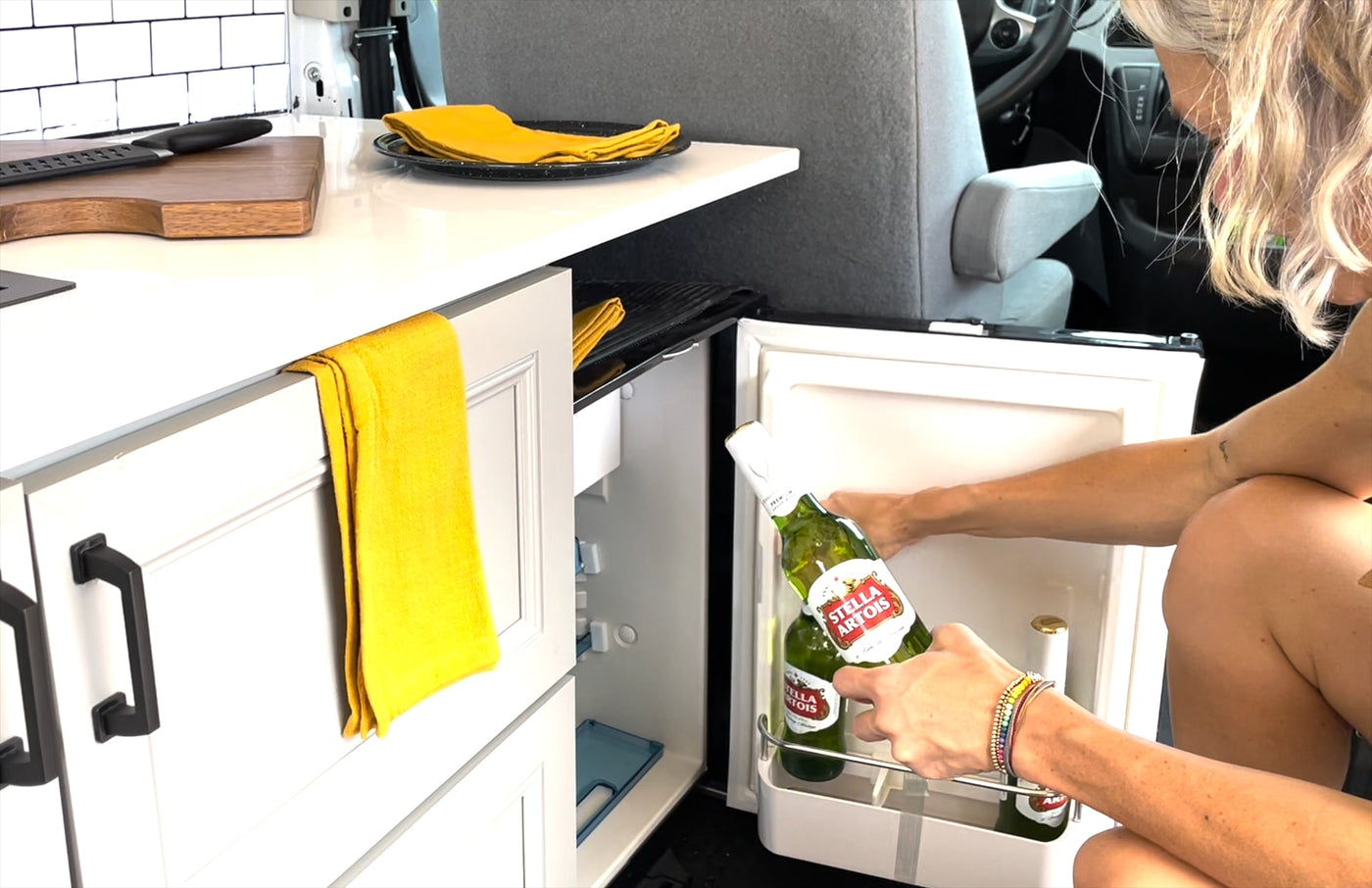 Grabbing cold Stella Artois from the RV rental fridge. Perfect for relaxing in this compact camper kitchen setup. — photo 12