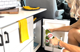 Grabbing cold Stella Artois from the RV rental fridge. Perfect for relaxing in this compact camper kitchen setup.