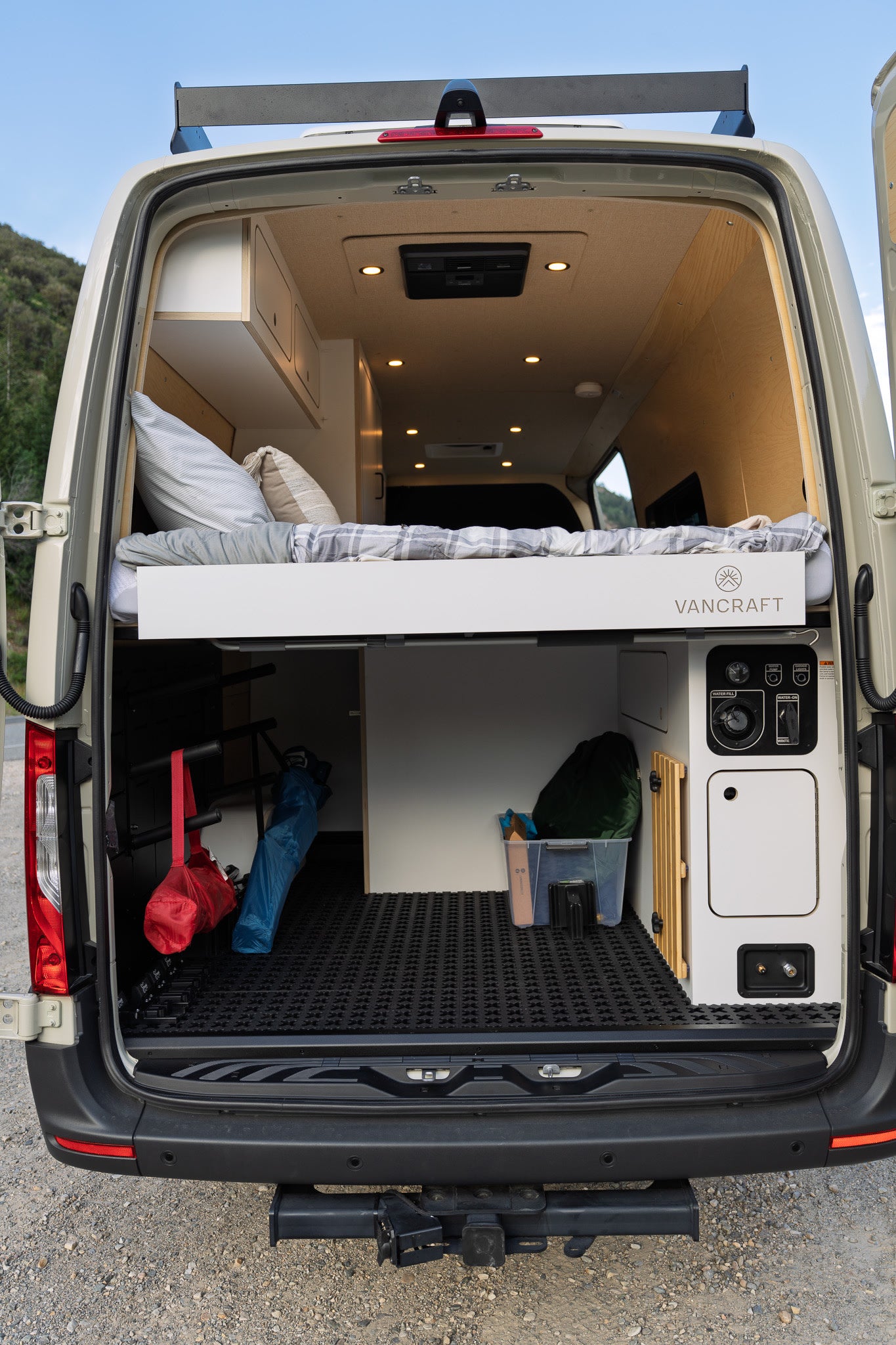 Spacious RV rental with smart interior design: raised bed, ample storage, and utility panel, perfect for mobile adventures.