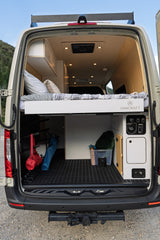 Spacious RV rental with smart interior design: raised bed, ample storage, and utility panel, perfect for mobile adventures.