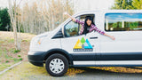 A happy woman leans out a white Wandervans RV rental campervan, ready for an exciting road trip adventure.