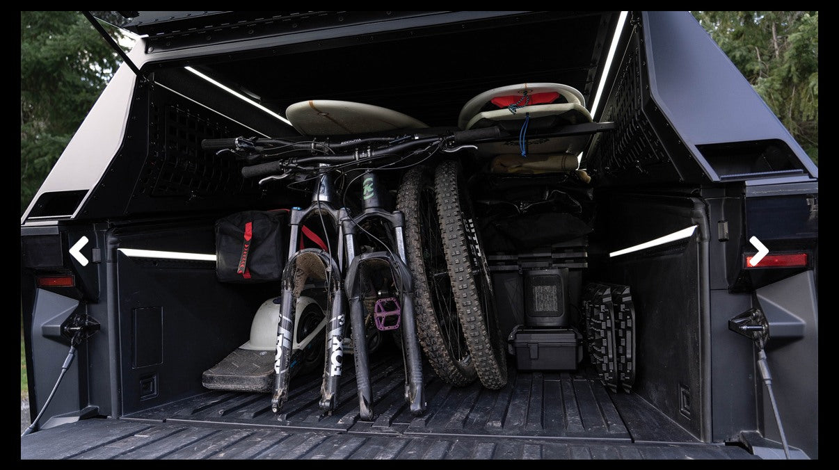 Optimal gear storage: Truck bed with bikes & boards under a lit canopy, ready for any RV rental journey.