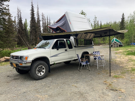 Overland camping setup: white pickup truck with rooftop tent & awning. Ideal for your next RV rental trip!