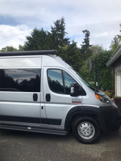 Silver Ram ProMaster camper van, a perfect RV rental parked on asphalt, ready for your road trip adventures.