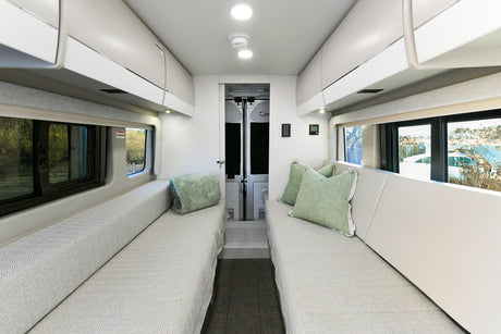 Spacious rv rental interior featuring facing sofas, overhead storage, and large windows for scenic views and comfortable travel.