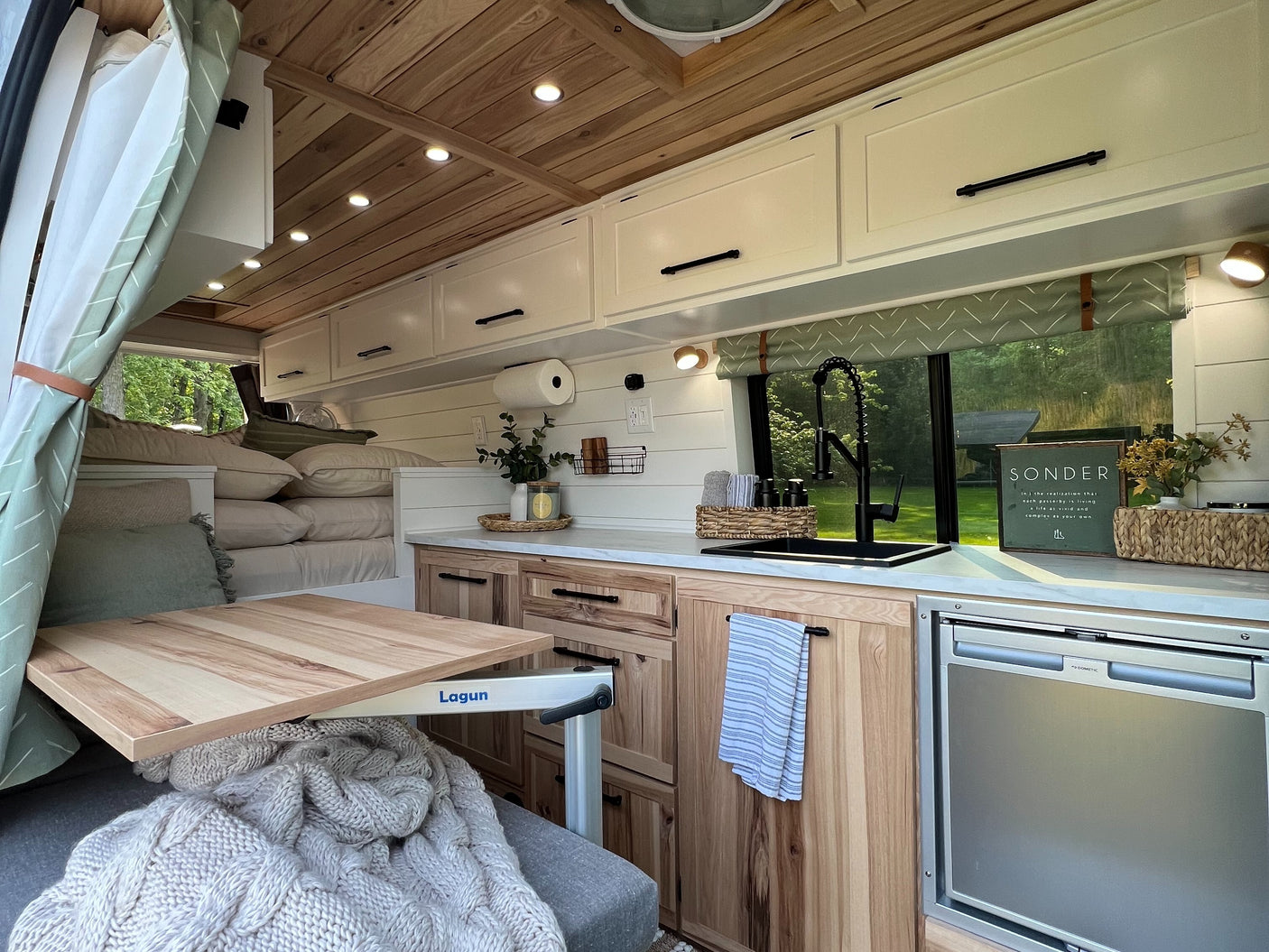 Cozy RV rental interior, featuring a well-equipped kitchen, wooden accents, and a clever Lagun table setup. Perfect home on wheels.