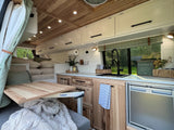Cozy RV rental interior, featuring a well-equipped kitchen, wooden accents, and a clever Lagun table setup. Perfect home on wheels.