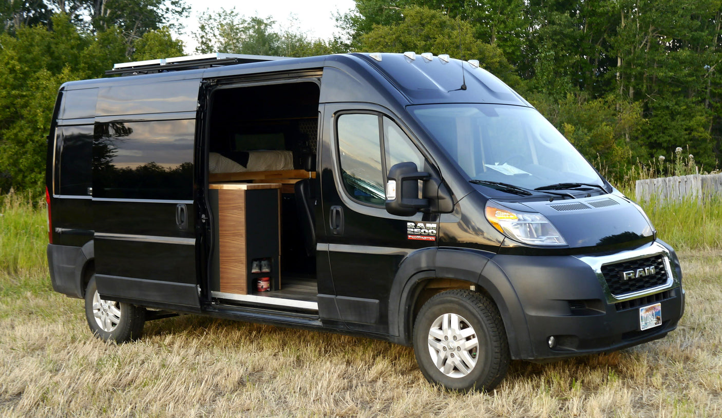 Black Ram ProMaster campervan with open side door, showcasing its converted interior. Ideal RV rental for outdoor adventures.