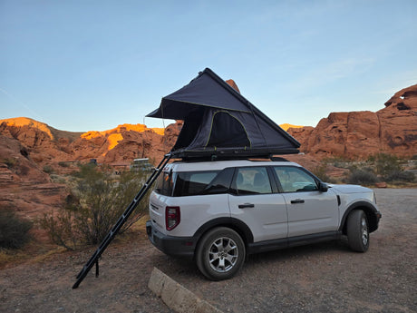 RV rental alternative: SUV with rooftop tent camping in scenic desert landscape. Perfect for outdoor adventure!