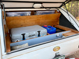 An rv rental teardrop camper's open galley features a cooler, water jugs, and clear bins, neatly organized for travel.