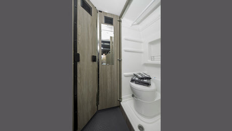 This RV rental features a compact wet bath with a toilet, shower, and a door with a mirror, maximizing space.