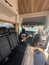 Inside this rv rental: a cozy camper van with black leather seating, warm wood accents, and a clear view of the dashboard.