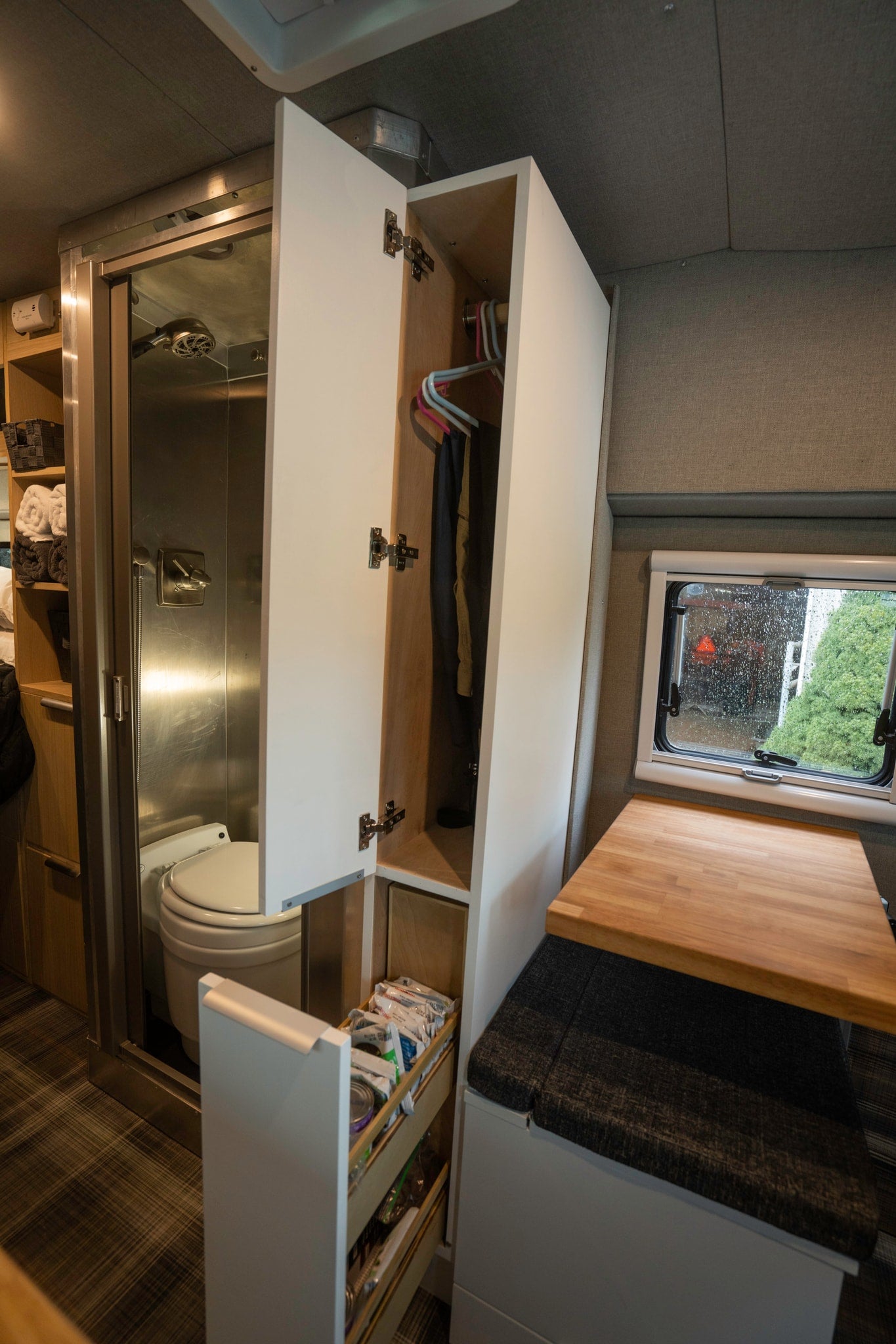 Inside an RV rental: a compact bathroom with shower/toilet, wardrobe, pull-out pantry, and cozy dining/work area. Smart space use. — photo 7