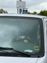 A white and brown dog is seen behind the steering wheel of an RV rental van, ready for a travel adventure.