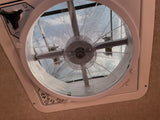 An RV rental ceiling fan with mesh screen and controls. The fan blades are visible through the screen, with sky beyond.