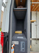RV rental interior: A well-equipped camper van utility area features electrical panels, organized storage, and a partial view of the shower.