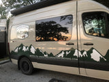 Customized adventure van for RV rental, featuring a mountain decal & sunset reflected in the window.