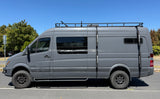 Side view of a rugged gray Mercedes Sprinter adventure van with off-road tires and roof rack, perfect for an RV rental.