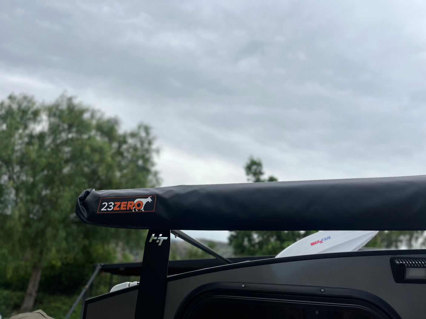 Close-up of a 23ZERO awning on an RV rental, with a visible MaxxFan and cloudy sky. Ready for your next adventure.