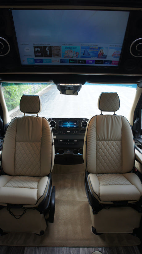 Luxurious RV rental interior with comfortable quilted seats and a large media screen for streaming entertainment.