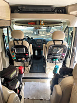 Inside an RV rental: front cabin with organized seats, child car seats, & overhead storage. Perfect for family road trips!