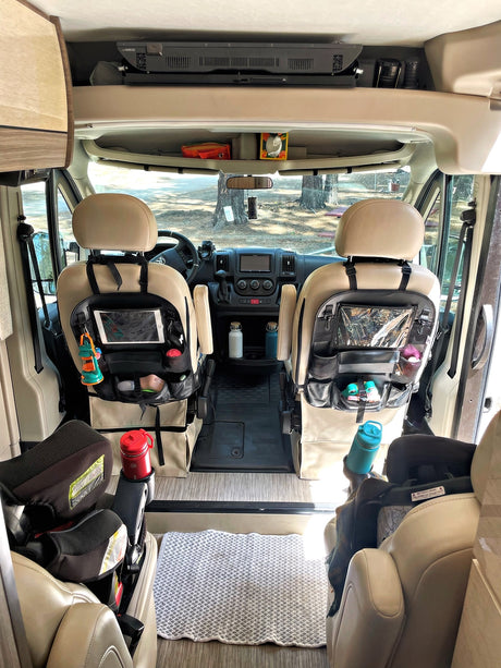 Inside an RV rental: front cabin with organized seats, child car seats, & overhead storage. Perfect for family road trips!