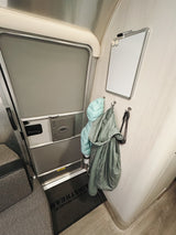 Airstream rv rental interior: entrance door, coats on hooks, magnetic whiteboard, and welcome mat.