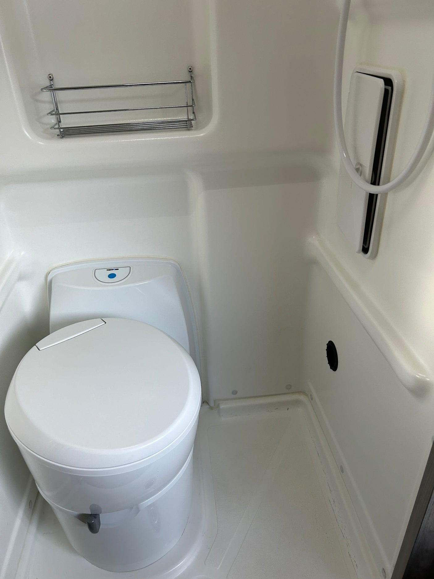 RV rental wet bath: Thetford toilet, shower, and chrome shelf. A compact and functional space.